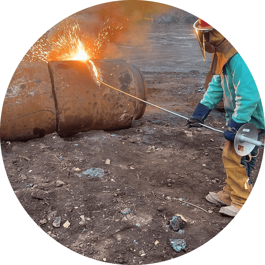 A worker is cutting a big piece of metal with a torch. Sparks are flying in all directions.